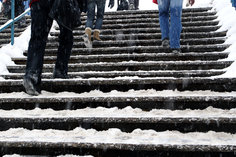 snow and ice covered stairs with people walking up them. 