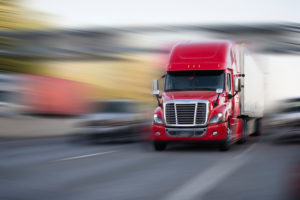 red modern big rig semi truck with semi trailer move with cargo on the highway 