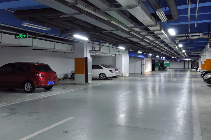 a basement parking lot with a red SUV and a white sedan style car in the background. 