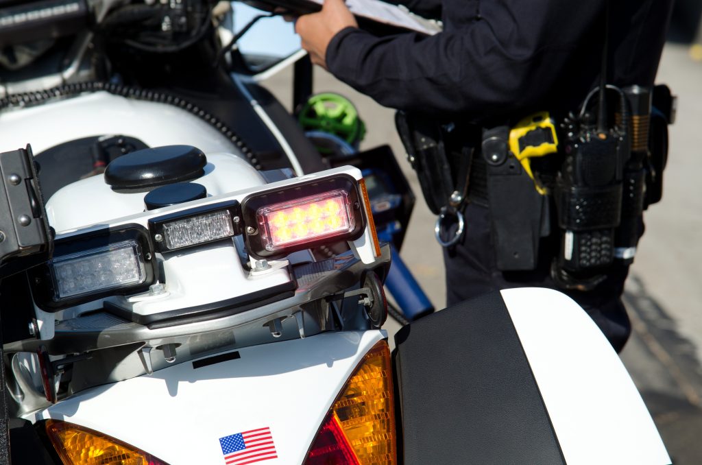 Police officer standing next to a motorcycle with holstered taser