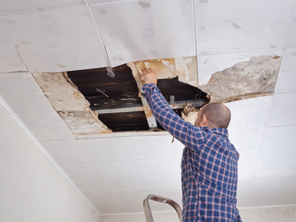Man examining a collapsed ceiling