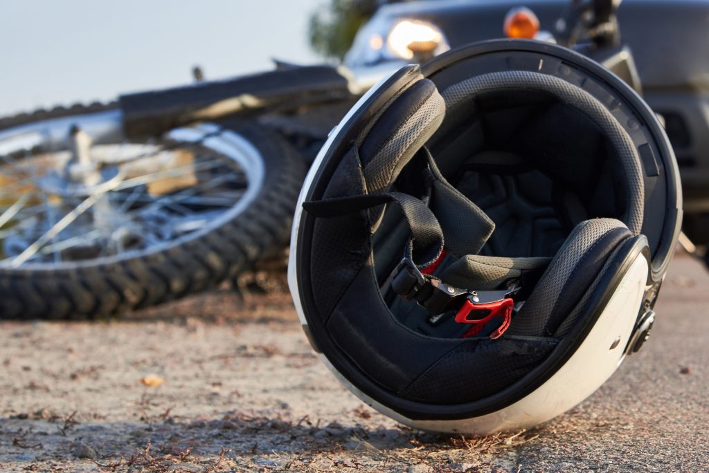 Photo of a wrecked motorcycle with the helmet in the foreground