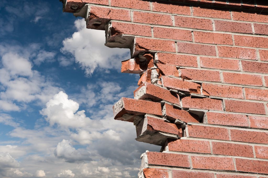 Broken brick wall and blue sky with clouds.